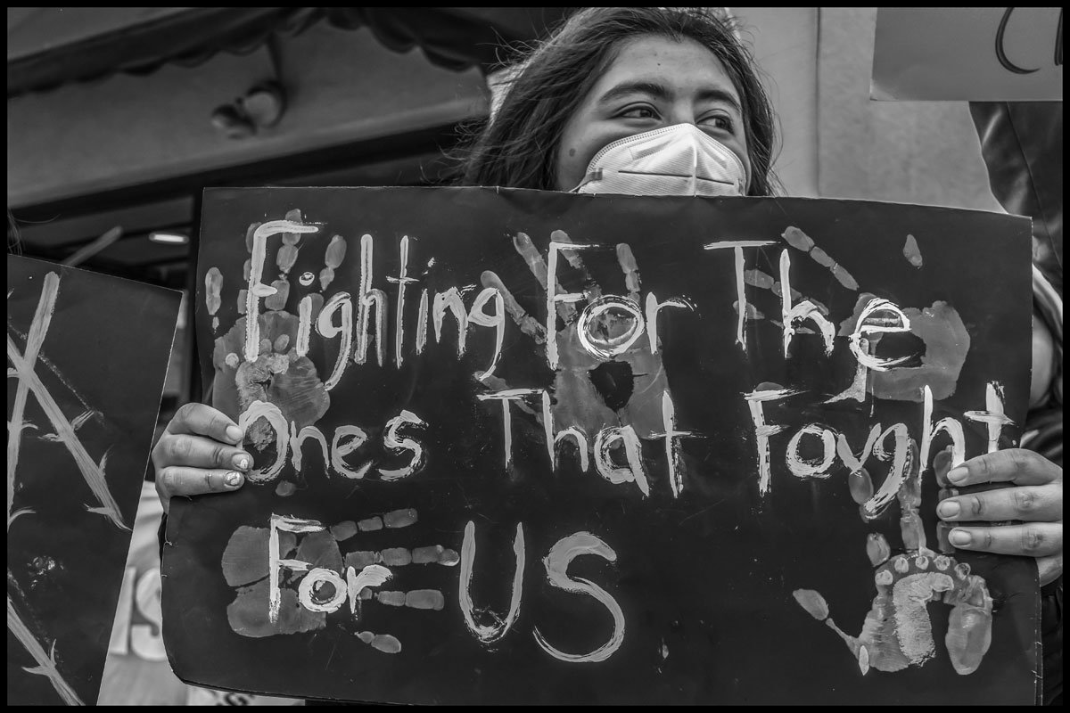 At a protest against immigration detentions in Santa Maria, CA, a young woman holds a sign honoring the work of her 168一分钟极速赛车官网 Farmworker parents. (Photo credit: David Bacom)